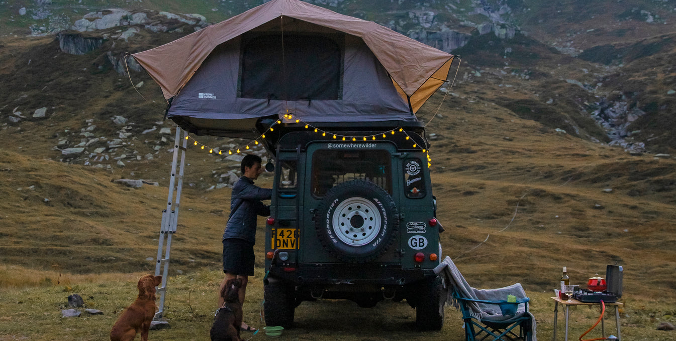 A man and his two dogs with their van camping setup.