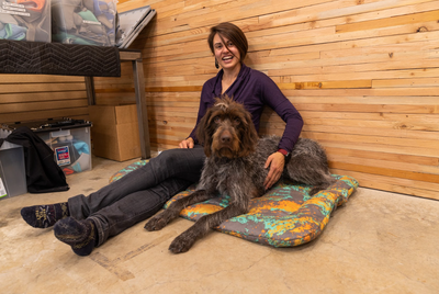 Kadee sits with her dog on a dog bed.